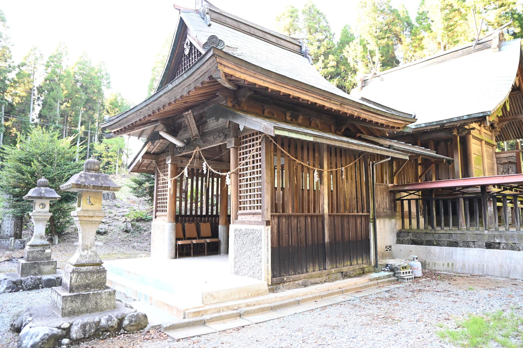 高く伸びた緑の木々の中に建つ、片俣阿蘇神社の写真