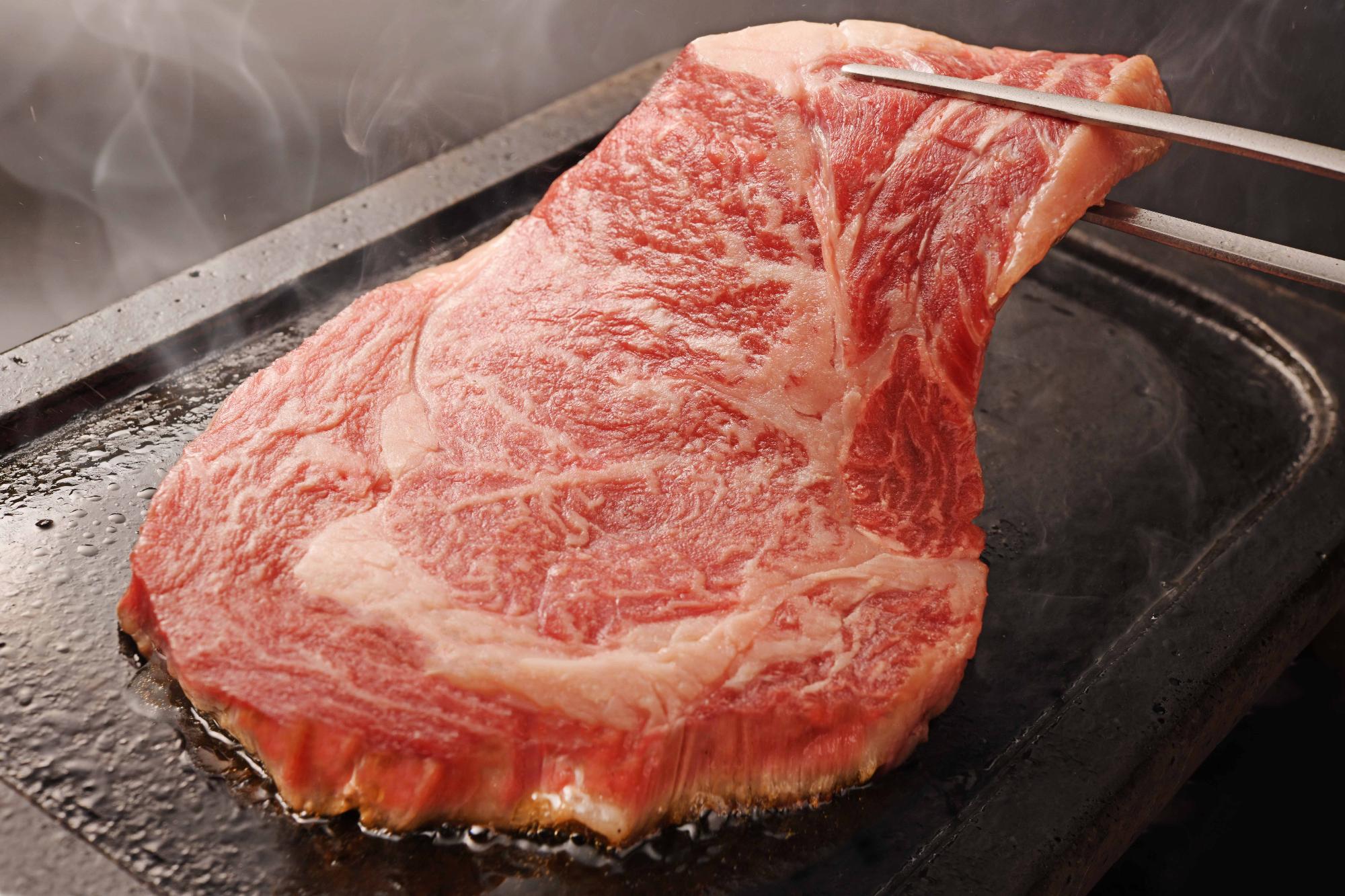 あか牛の肉を鉄板で焼いている写真
